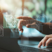 Seorang individu sedang menggunakan laptop dengan ikon digital melayang di atas layar, termasuk folder, dokumen, awan penyimpanan, daftar centang, roda gigi, dan koneksi jaringan—melambangkan manajemen data dan alur kerja digital dalam suasana profesional yang terang dan modern.